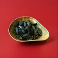 Dutch black double salted liquorice in the shape of a fish in a gold bowl on a red background 