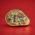 Individually wrapped hard boiled red yellow and blue tutti fruity lolly in a gold bowl on a red background 