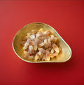 Brown and white bottle shaped cola flavoured jelly sweets with a fizzy sugar coating in a gold bowl with a red background 
