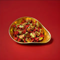 Individually wrapped red and gold Brazil nut flavoured toffees in a gold bowl on a red background