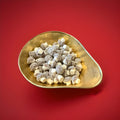 Mushroom shaped fondant with coconut and cocoa dusting  in a gold bowl with a red background 