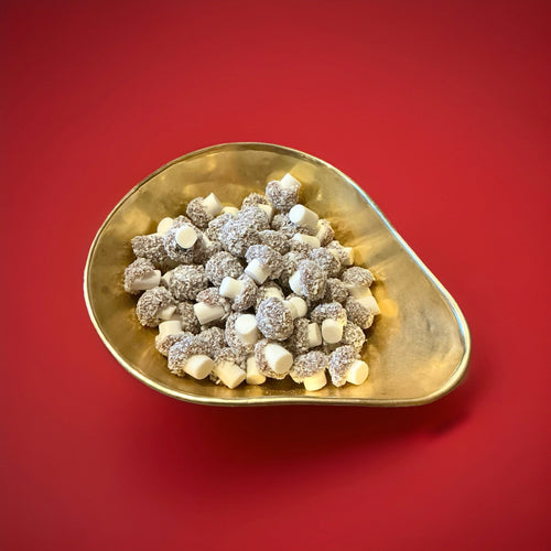 Mushroom shaped fondant with coconut and cocoa dusting  in a gold bowl with a red background 