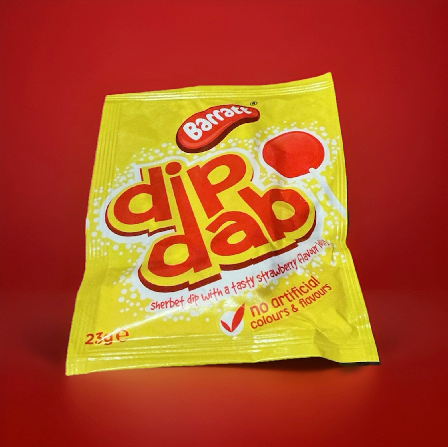 A yellow and red paper dip dab packet with a red lolly and white sherbet inside on a red background 