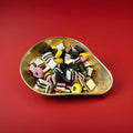 Liquorice allsort sweets in a gold bowl on a red background 