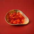 Hard boiled oval shaped throat and chest sweets in an orange wrapper in a gold bowl on a red background 