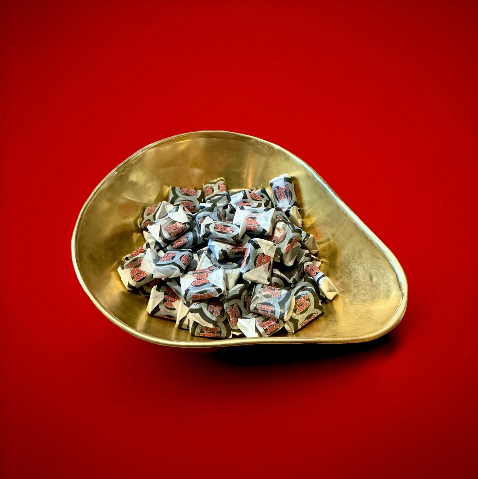Barratt black jack aniseed flavoured chews in a gold bowl on a red background 