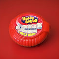 Strawberry flavoured bubblegum tape in a red plastic case on a red background 
