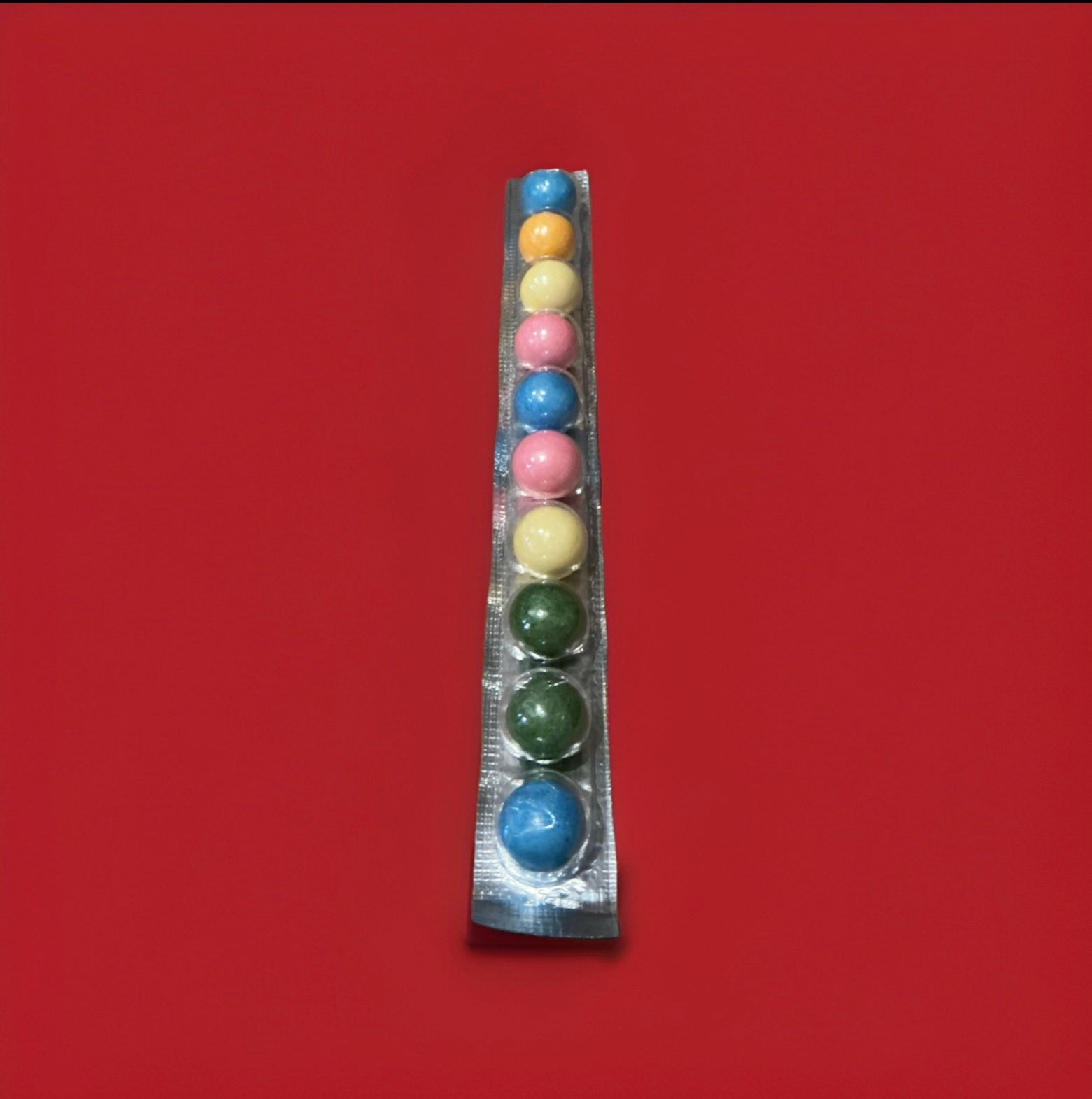 10 mixed colours of round bubblegum balls in a foil strip on a red background 