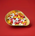 Multicoloured sugared almonds in a gold bowl on a red background 