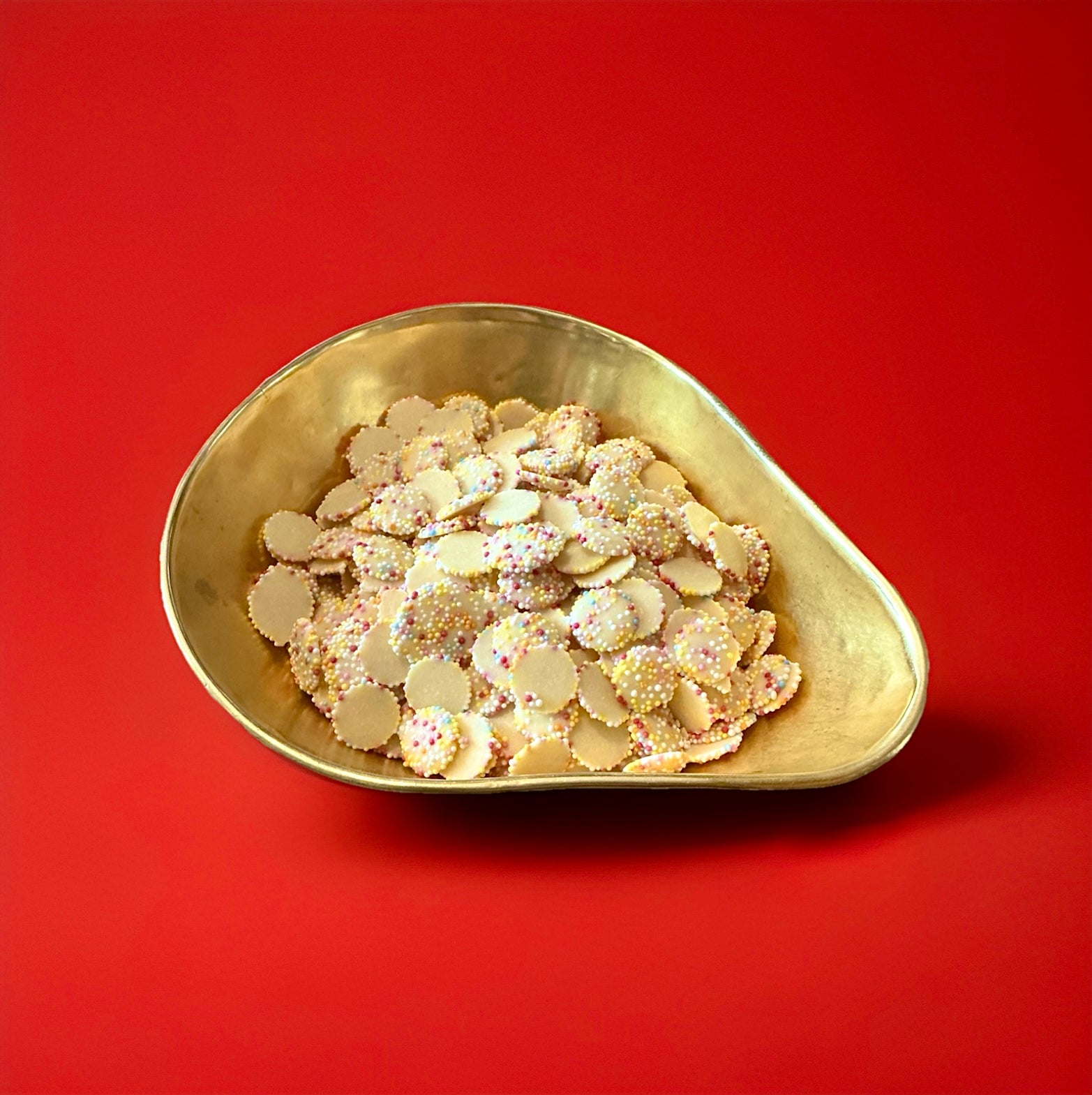 White chocolate flavoured snowies in a gold bowl on a red background 
