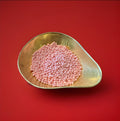 Pink coloured raspberry flavoured millions in a gold bowl on a red background 
