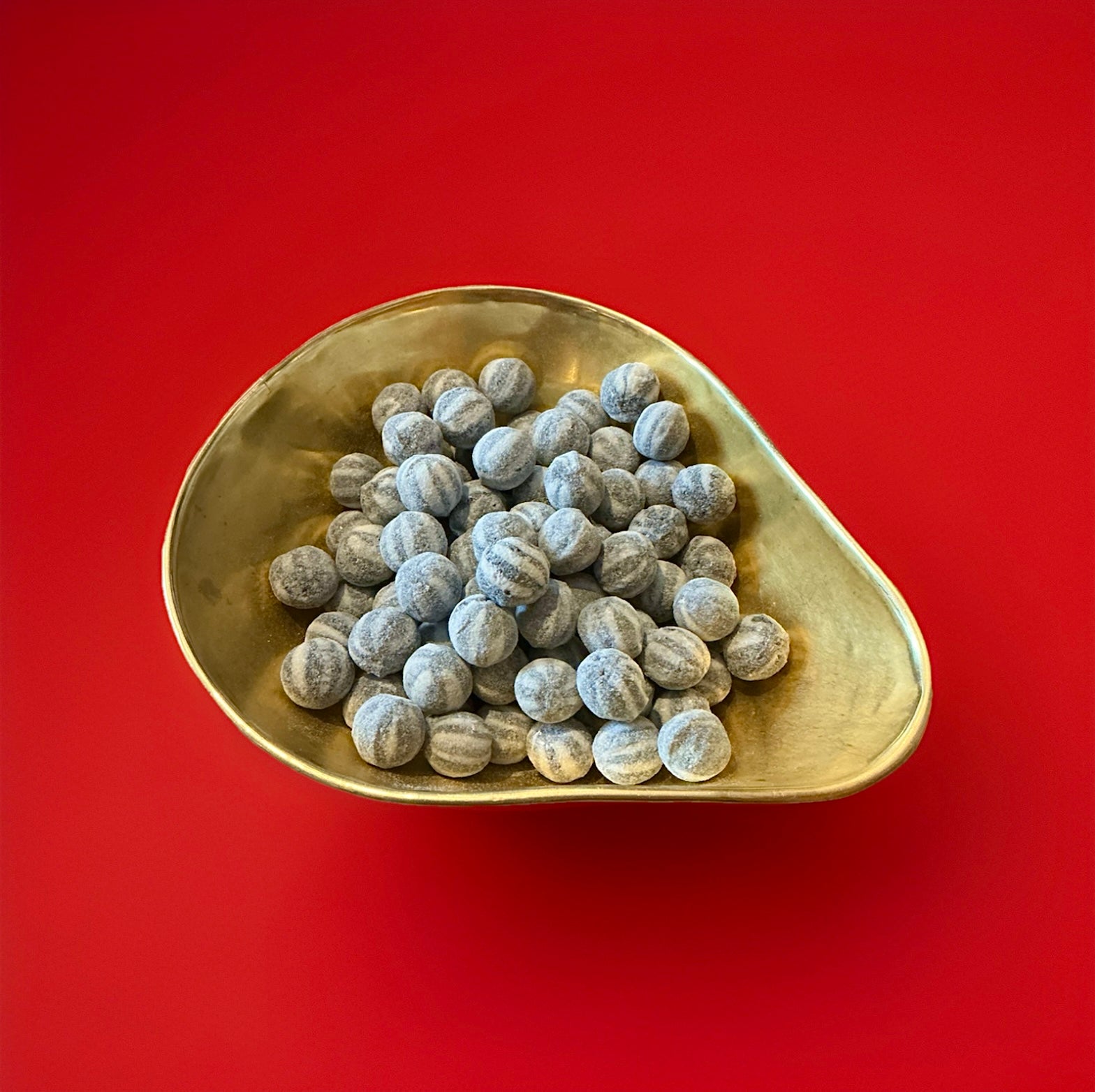 Round hard boiled black and white striped bulls eyes mints in a gold bowl on a red background 