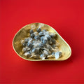 Individually wrapped hard boiled brown coloured black bullet mints in a gold bowl on a red background 