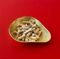 Sticks of brown coloured chopped aniseed flavoured colts foot rock in a gold bowl on a red background 