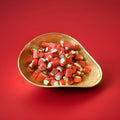 Red and green rhubarb flavoured rock cuttings in a gold bowl with a red background 