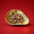 Pieces of toffee crumble chocolate and toffee pellets in a gold bowl on a red background 