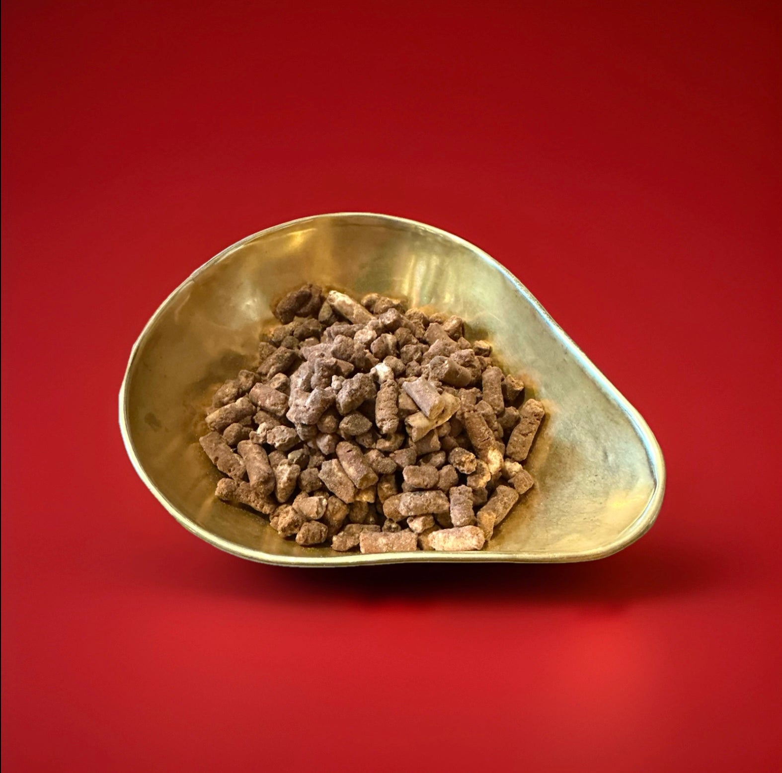 Pieces of toffee crumble chocolate and toffee pellets in a gold bowl on a red background 