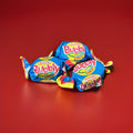 Individually wrapped pink bubblegum in a yellow pink and blue wrapper twisted at both ends on a red background 