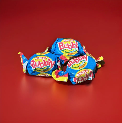 Individually wrapped pink bubblegum in a yellow pink and blue wrapper twisted at both ends on a red background 