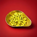 Yellow coconut roll with a black liquorice centre in a gold bowl on a red background 