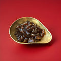 Rich buttery caramelised toffee hard boiled sweets in a gold bowl with a red background 