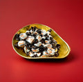 Individually wrapped white and brown treacle flavoured toffees in a gold bowl on a red background