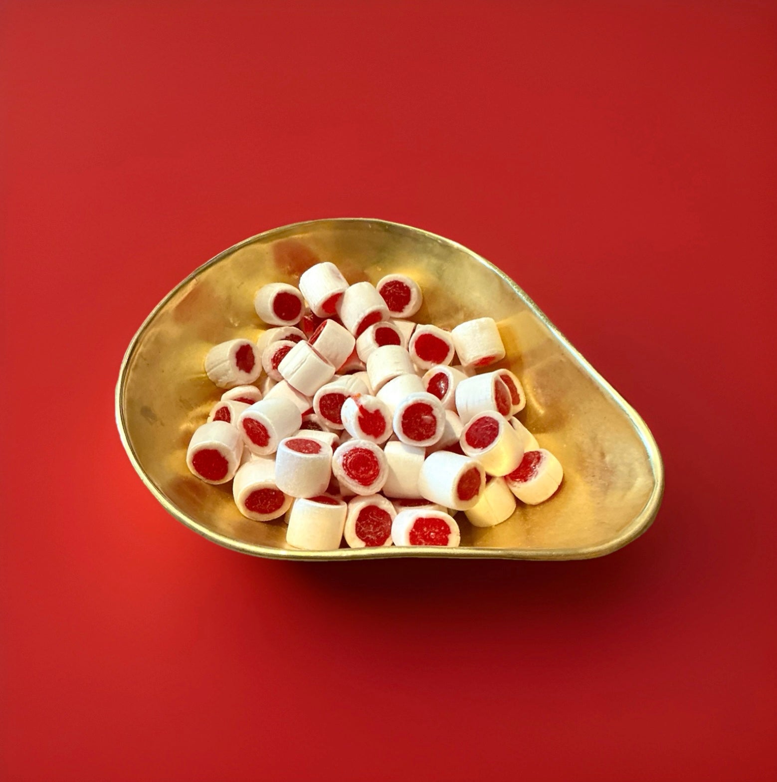 Traditional white and red rock cuttings with a clove flavour in a gold bowl with a red background 