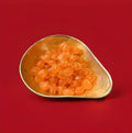 Orange coloured round hard boiled sweets with a sharp brandy flavour in a gold bowl with a red background 