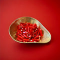 Red strawberry flavoured liquorice tubes filled with white fondant in a gold bowl on a red background 