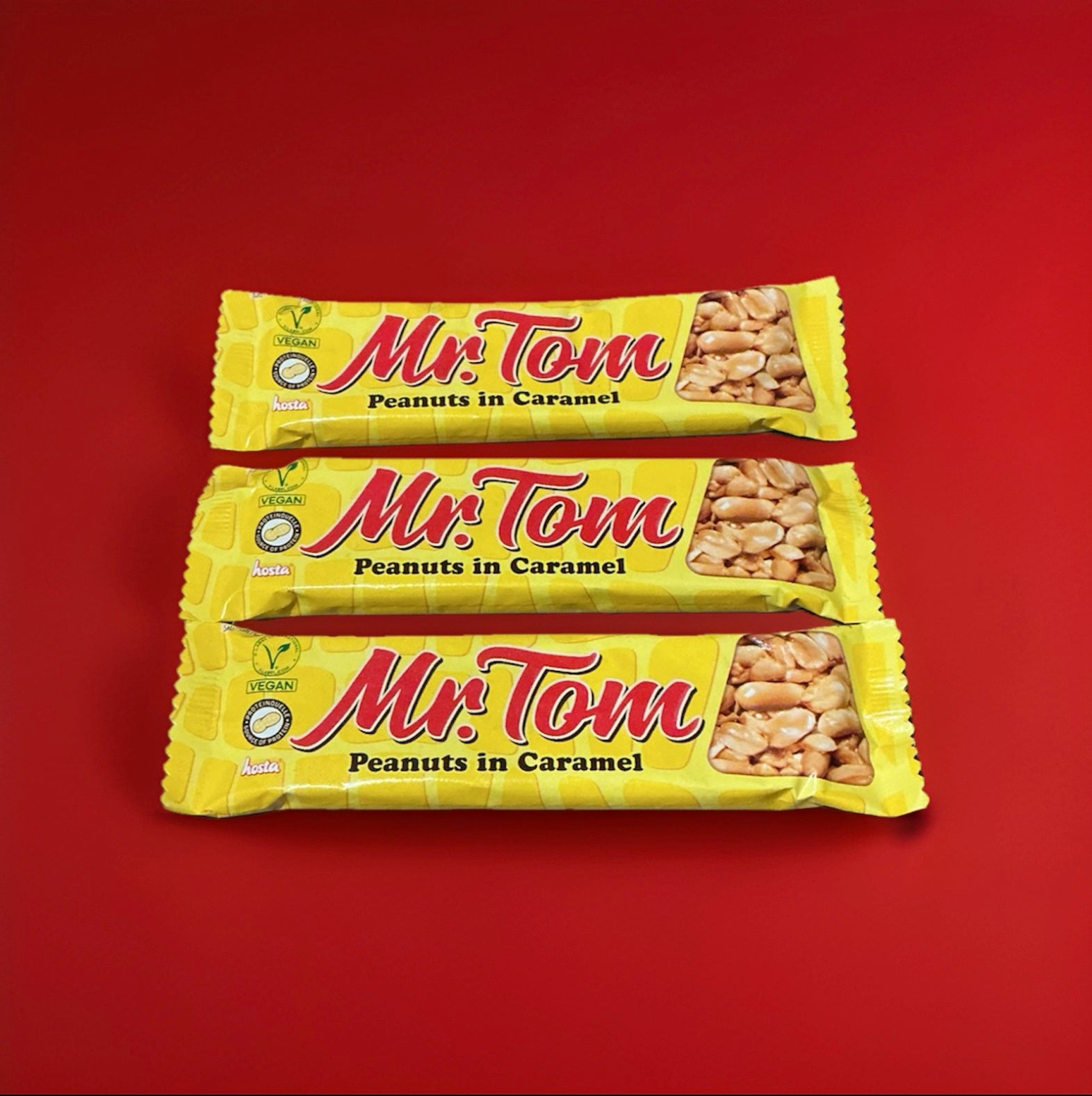 Mr toms peanut brittle bar in a yellow and red wrapper on a red background 