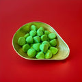 Large bright green marshmallows coated in sugar in a gold bowl with a red background 