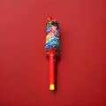 Hard boiled strawberry flavour whistle lolly with a plastic stick in a blue and red wrapper on a red background 