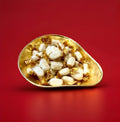 Individually wrapped white hard boiled mints with a chocolate centre in a gold bowl on a red background 