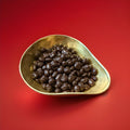 Carol Anne dark chocolate coated cranberries in a gold bowl with a red background 