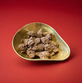 Milk chocolate covered coconut macaroon clusters in a gold bowl on a red background 