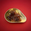 Giant cola bottle jelly sweets in a gold bowl on a red background 