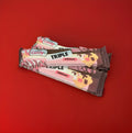 Pink white and brown triple nougat bar in a pink white and brown wrapper on a red background 