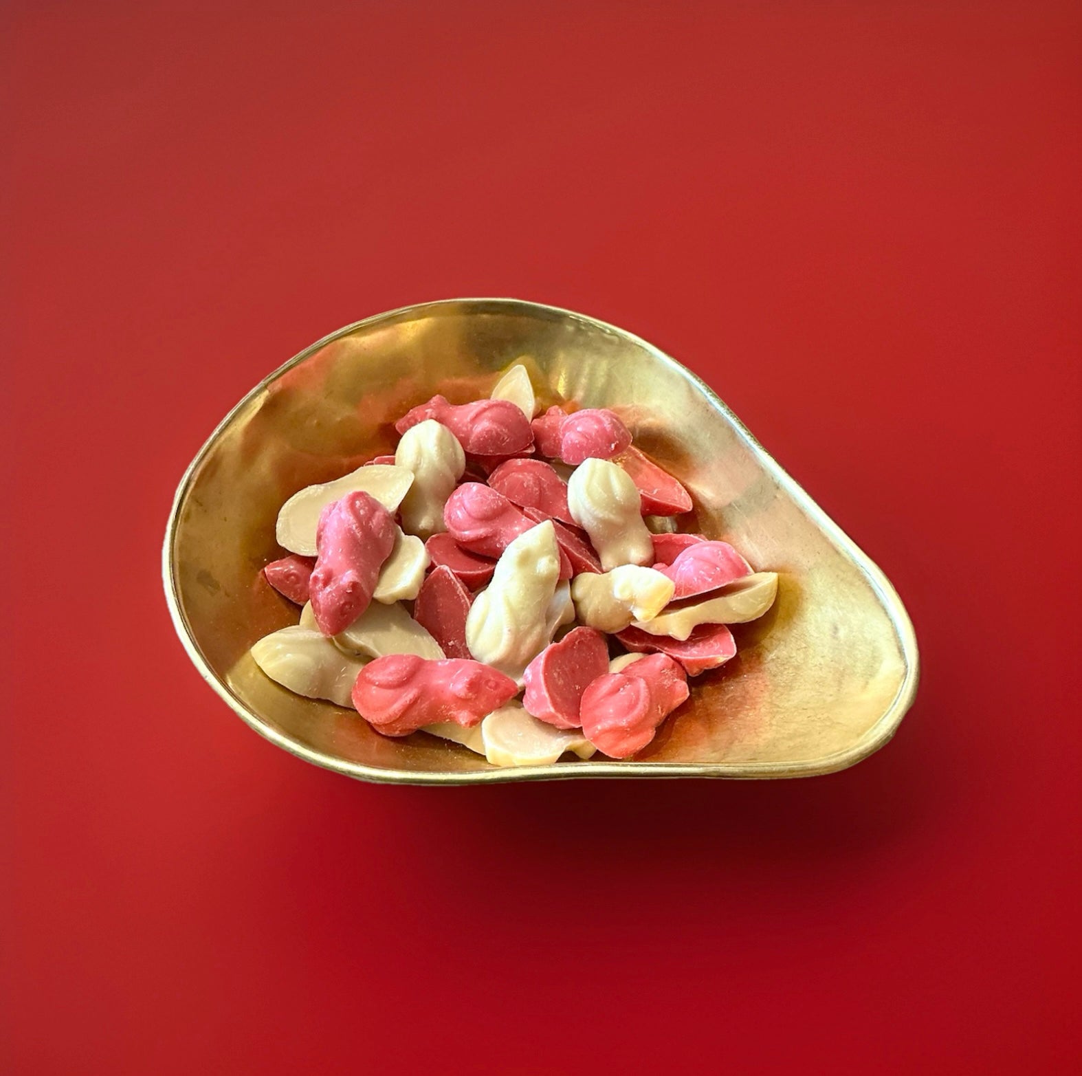Pink and white colour chocolate mice in a gold bowl on a red background 