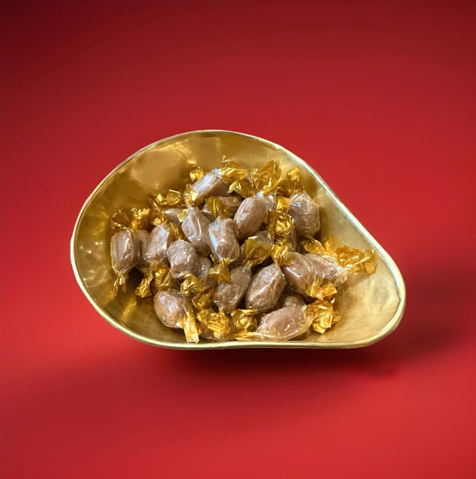 Invalid toffees individually wrapped oval shaped in a gold bowl with a red background 