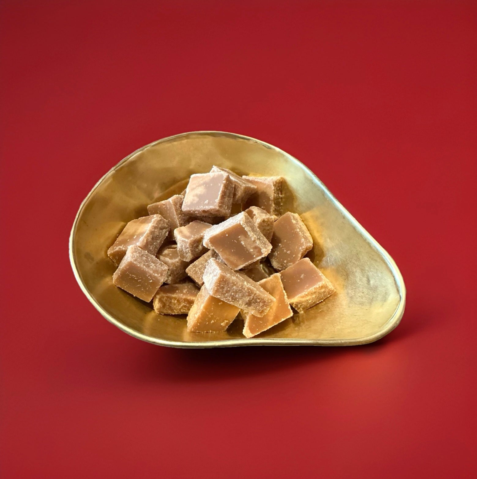 Chunks of Scottish tablet butter fudge in a gold bowl on a red background 