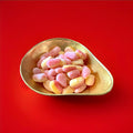 Large hard boiled pear drops in a gold bowl on a red background 