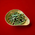 Green and pink liquorice and fondant tubes with a sour sugar coating in a gold bowl with a red background 