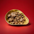 Dried banana chips coated in milk chocolate in a gold bowl on a red background 