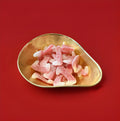 Red and white fang shaped jelly sweets with a sour sugar coating in a gold bowl with a red background 