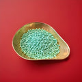 Green coloured apple flavoured millions in a gold bowl on a red background 