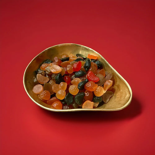 Fruit shaped fruit flavoured Lion Fruit Salad sweets in a gold bowl with a red background 