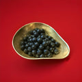 Hard boiled cinnamon ball sweets in a gold bowl on a red background 