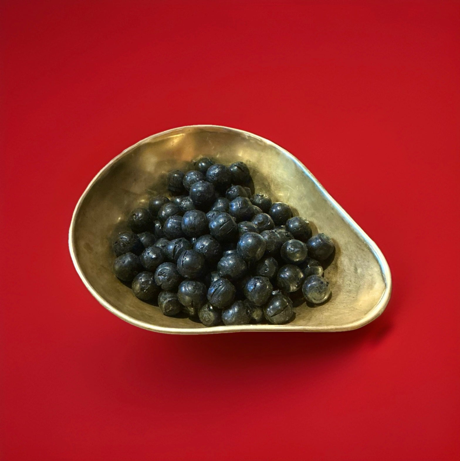 Hard boiled cinnamon ball sweets in a gold bowl on a red background 