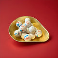 Large white red and blue round gobstopper in a gold bowl on a red background 