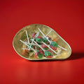 Hard boiled individually wrapped red and green watermelon lolly in a gold bowl on a red background 